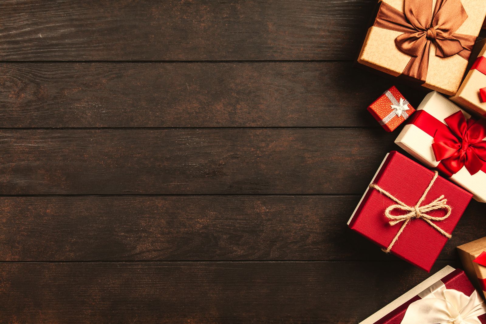 Wrapped red and gold gifts with ribbon bows on a dark wooden table, ideas for baby's first Christmas gifts UK