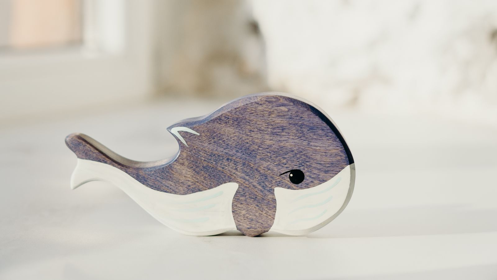 Hand-painted wooden whale toy standing on a pale surface, birthday gifts for 3 year olds UK