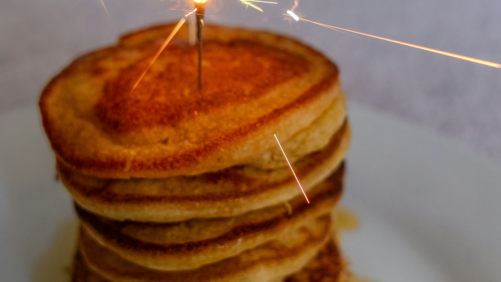 A stack of pancakes with a lit sparkler on top &mdash; birthday morning surprise ideas for kids