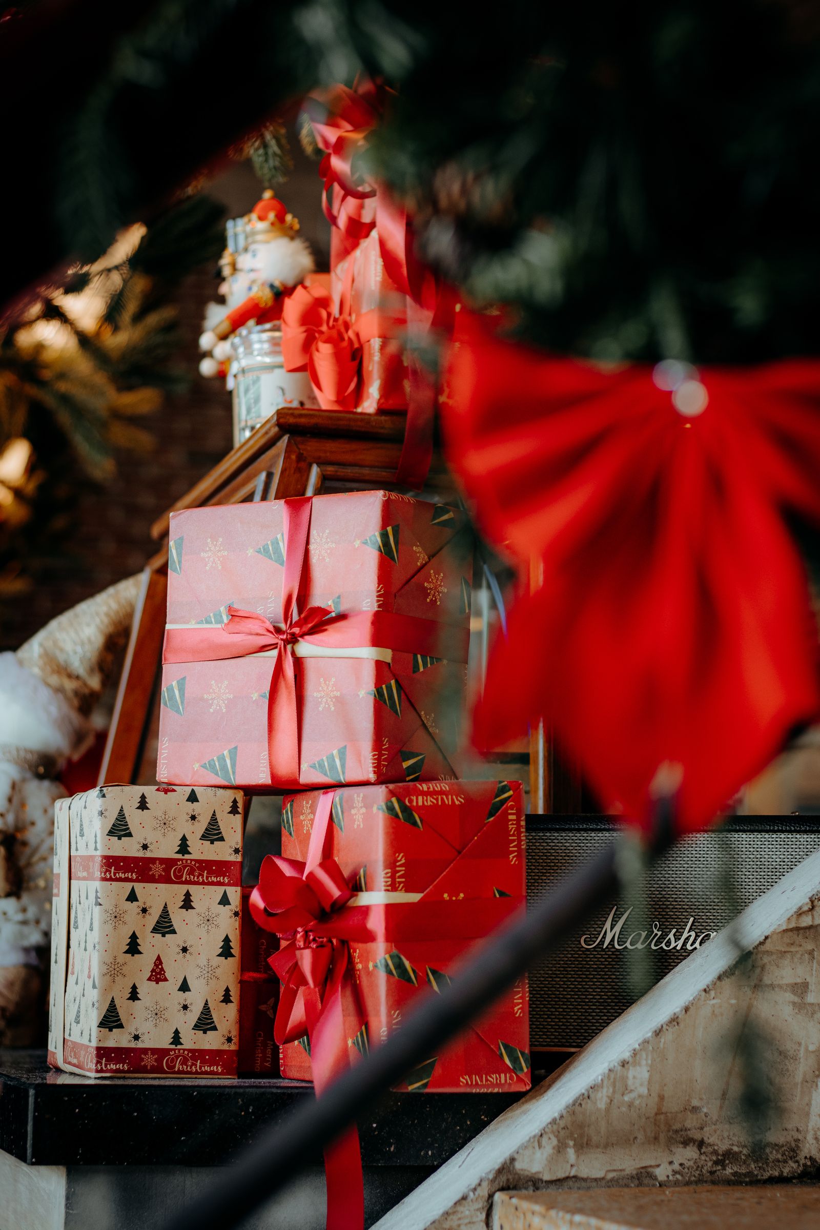 Stack of wrapped Christmas gifts with red ribbons under a decorated tree, ideal for personalised Christmas gifts for kids UK