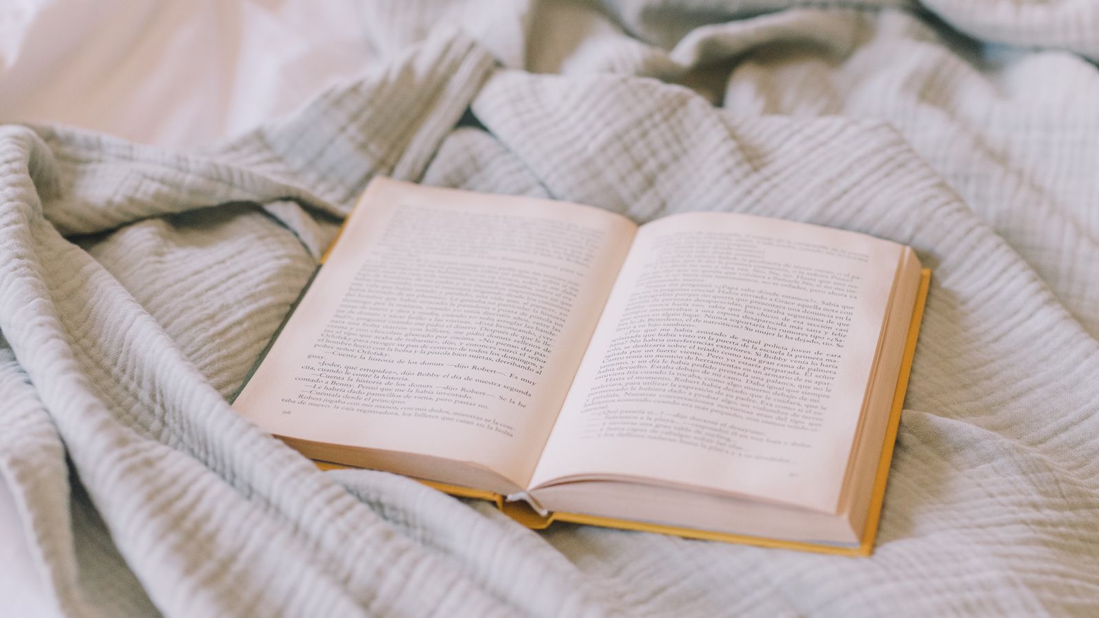 An open book resting on a soft cream blanket — birthday gifts that aren't more plastic