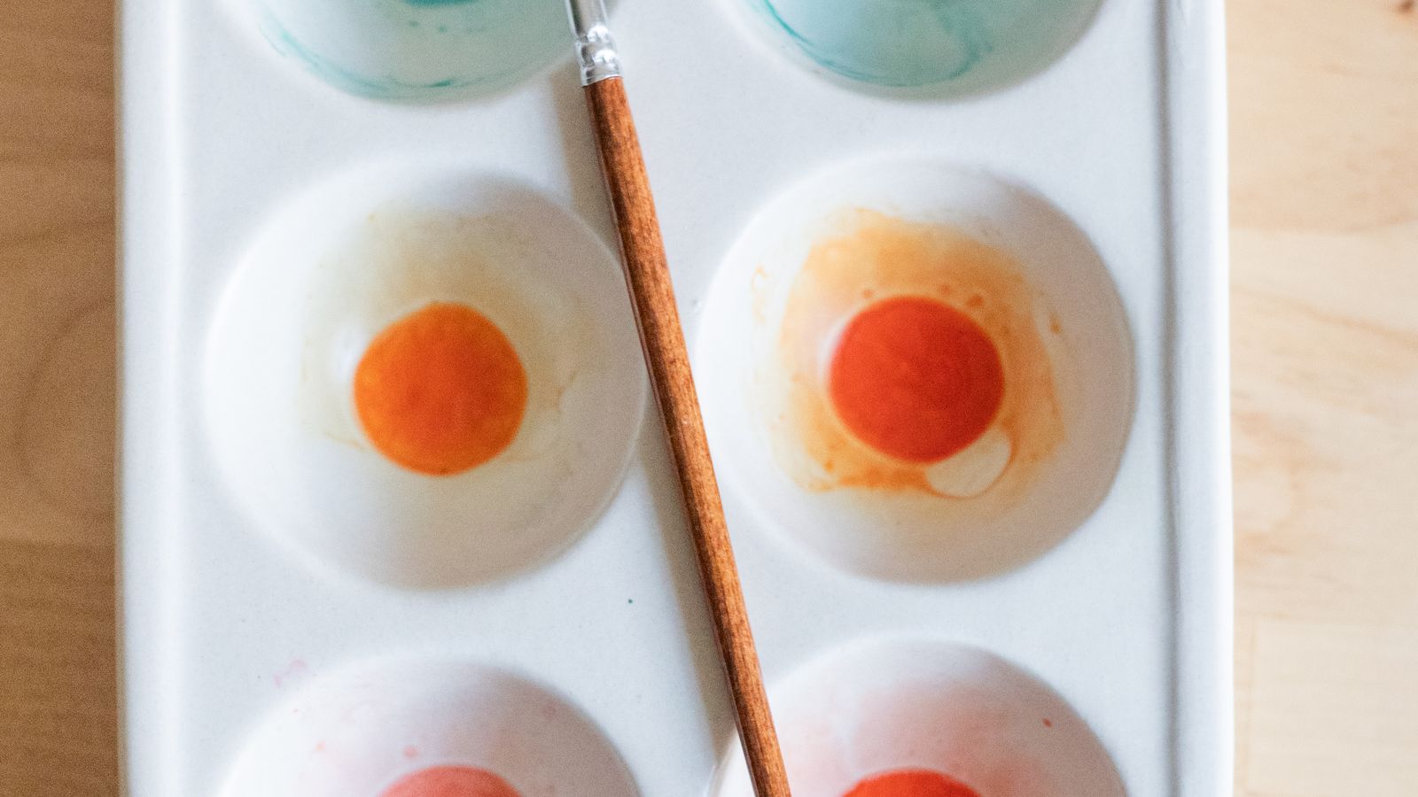 Watercolour paint palette and brush on a wooden table — meet the characters behind our animations