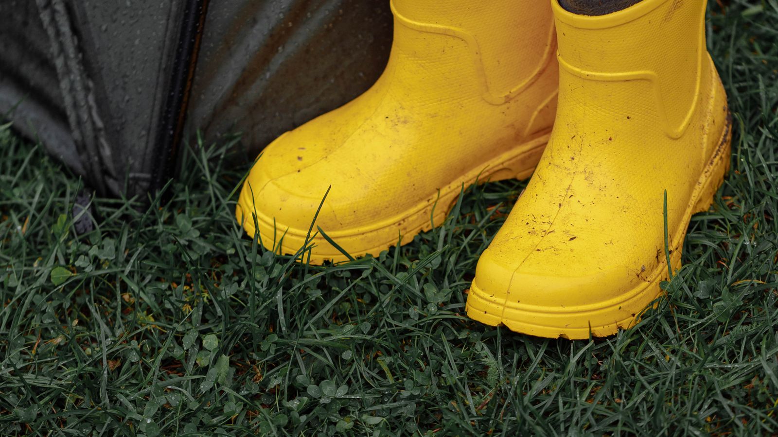 A pair of child&rsquo;s yellow wellington boots on wet grass &mdash; non-toy gifts for kids UK