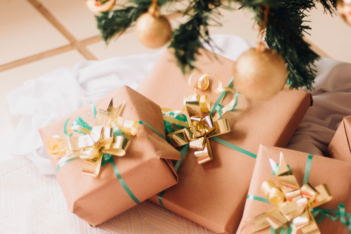 Kraft-paper wrapped Christmas presents with gold bows under a decorated tree, ideas for personalised Christmas gifts for grandchildren UK